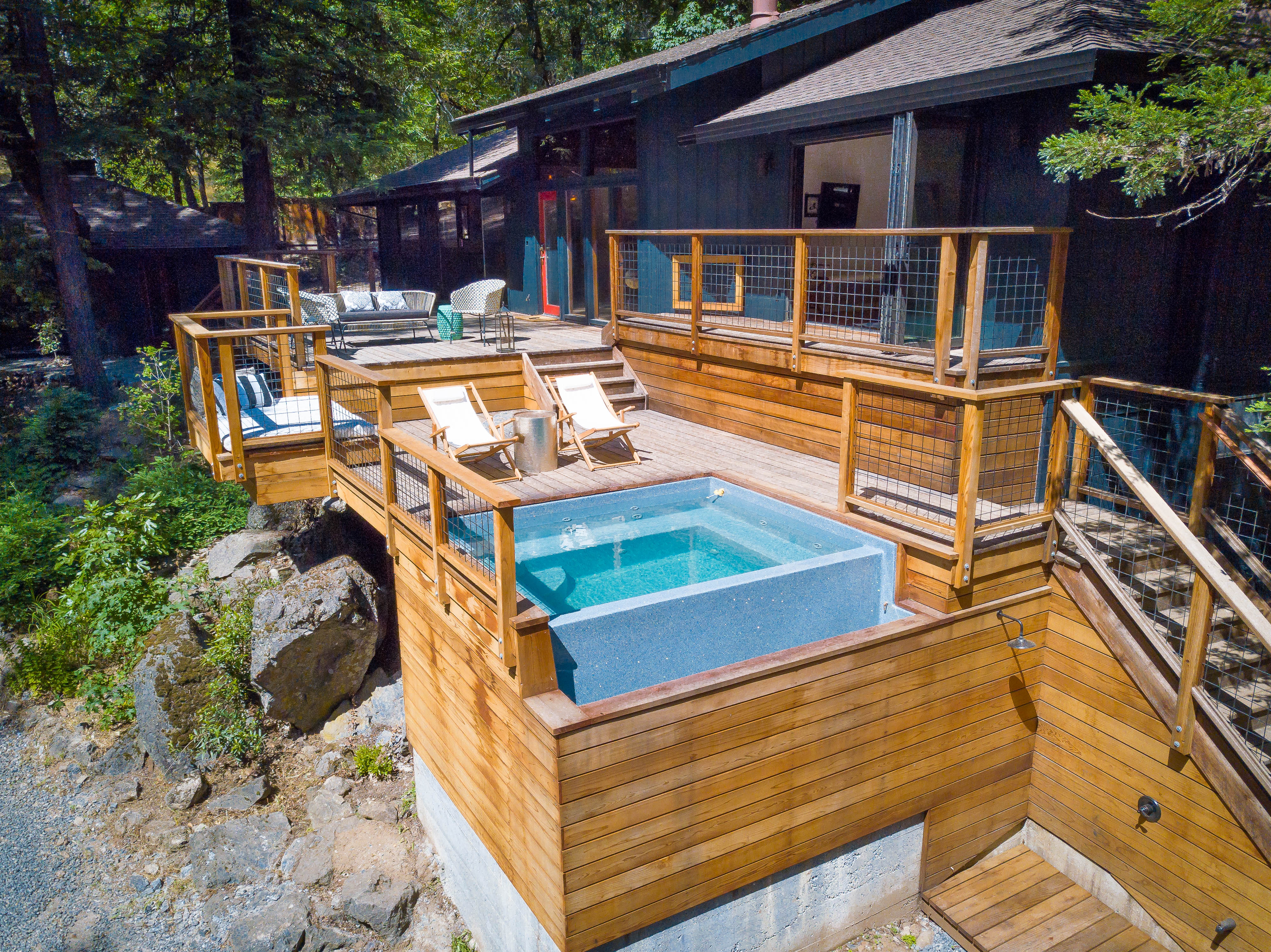 The plunge pool set into the cedar deck at Cosmico, with the cabin and redwoods behind
